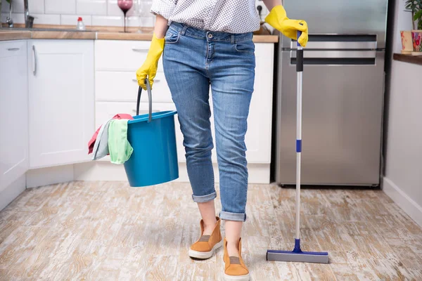 Vrouw met dweil en emmer met schoonmaakmiddelen thuis — Stockfoto