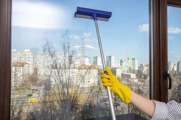 hand cleaning glass window. A female hands in bright yellow gloves washes the windows