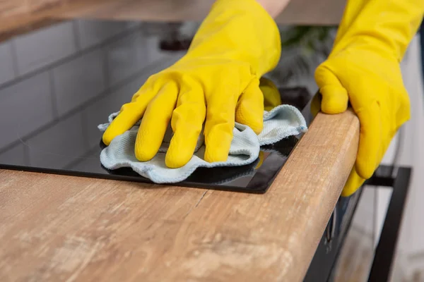 Giovane donna mani pulizia di un moderno piano cottura a induzione nero da uno straccio, lavori domestici — Foto Stock