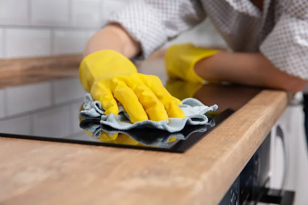 Handen van de jonge vrouw een moderne zwarte inductie kookplaat schoonmaken door een doek, huishoudelijk werk — Stockfoto