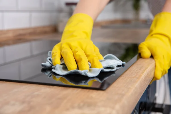 Handen van de jonge vrouw een moderne zwarte inductie kookplaat schoonmaken door een doek, huishoudelijk werk — Stockfoto