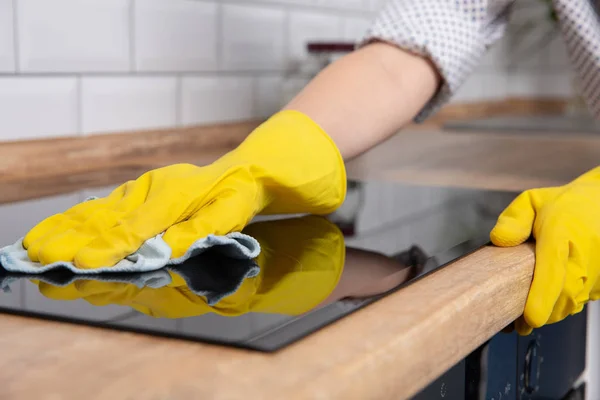 Handen van de jonge vrouw een moderne zwarte inductie kookplaat schoonmaken door een doek, huishoudelijk werk — Stockfoto