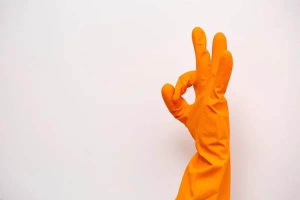 Ok sign of orange rubber gloves. Preparing for cleaning. Hands clean after cleaning. Squeaky people. Rubber gloves on the hand. Rubber gloves on a hand on a white background.