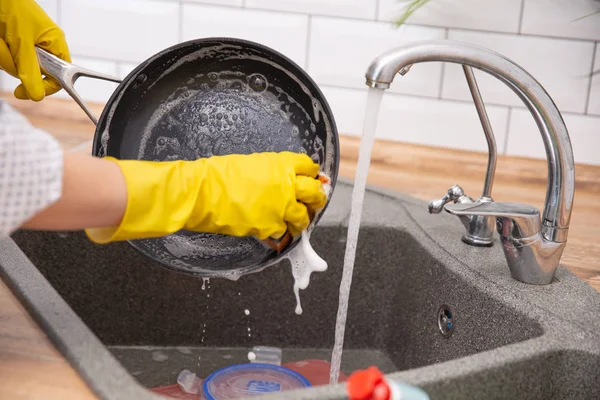 El yıkama kızartma tavası. Genç ev hanımı kadın yıkama zor durumda bir mutfak lavaboda bir sünger, el temizliği, el, el, ev işi bulaşık makinesi — Stok fotoğraf
