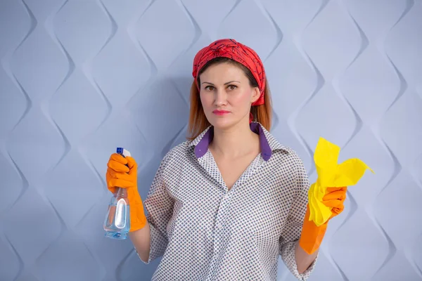 Vrouw huisvrouw met het schoonmaken van de spray fles en doek in de hand op blauwe achtergrond — Stockfoto