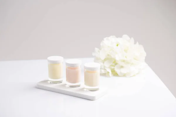 Drei Gläser Hautpflege-Kerzencreme mit natürlichen frischen Sommerblumen — Stockfoto