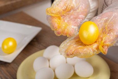 Kadın elleri, çalışma yüzeyinde sarı renkte yumurta boyuyor.