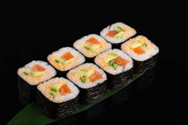 Muz yaprağı üzerinde avokado, salatalık ve somon ile Maki suşi