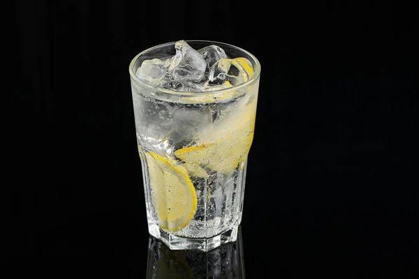 Cold cocktail with lemon. A glass of dew drops. Freshness, alcohol, bar. Black background — Stock Photo, Image