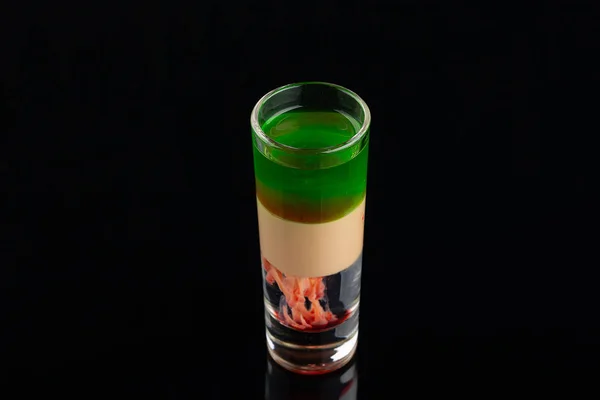 Green alcoholic shot glass with absent, irish cream, liquor on elegant dark black background.