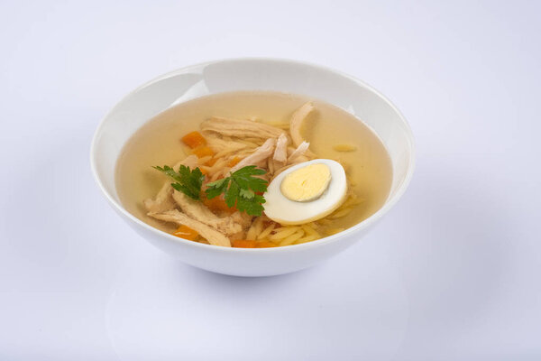 bowl on a table with chicken herbs, gg and noodles soup