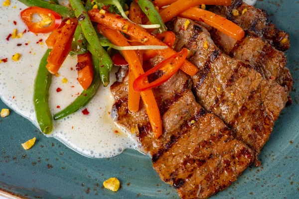 Bifteky z grilovaného hovězího masa s chřestem a mrkví podávané v restauraci — Stock fotografie