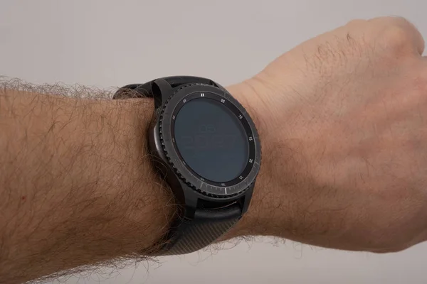 male hand wearing smart watch with blank screen on grey