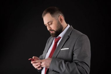 İşadamı iyi bakımlı adam akıllı telefon tutun. Adam resmi takım kullanımı akıllı telefon sosyal ağlar. Adam sörf İnternet Smartphone siyah arka plan. Çevrimiçi hizmet ve uygulama. Modern teknolojiler.