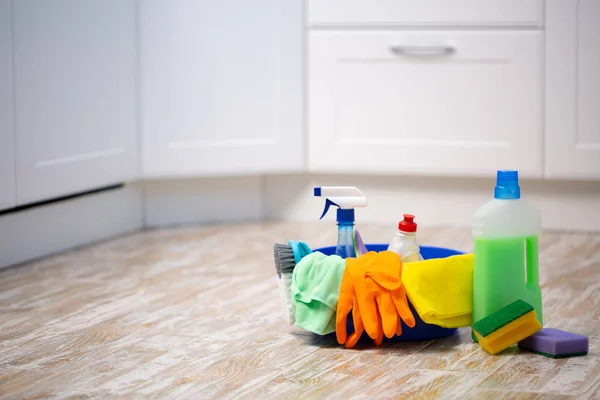 Set of cleaning supplies on floor in kitchen. Space for text