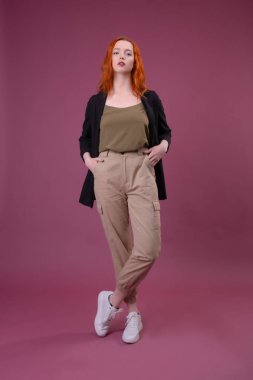 Pembe arka plan üzerinde duran genç bir kızın tam uzunlukta portre