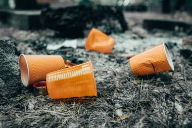 Turuncu tek kullanımlık Plastik cam veya bardak bir çöp kutusunda içme suyu için kullanılan - Çevre sorunu kavramı. Kompostedilemeyen atıklar