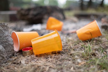 Turuncu tek kullanımlık Plastik cam veya bardak bir çöp kutusunda içme suyu için kullanılan - Çevre sorunu kavramı. Kompostedilemeyen atıklar