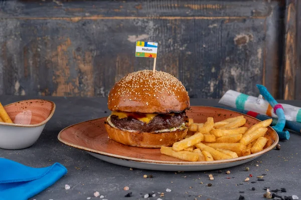 Craft beef burger with sesame bun and french fries on stone background. — Stock Photo, Image