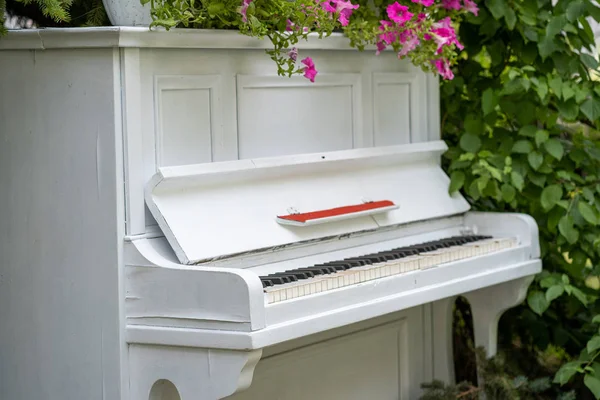 Das weiße alte, mit Blumen geschmückte Klavier — Stockfoto