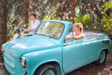 Eski bir arabada iki kadın. Retro moped üzerinde bir retro Convertible ve yetişkin kızı mutlu kıdemli anne