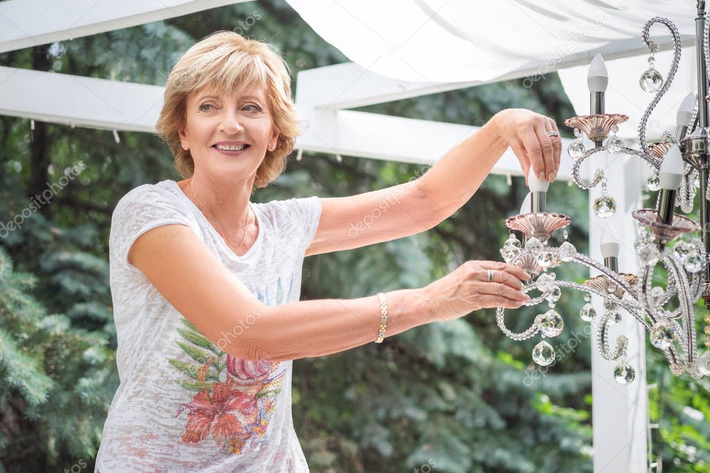 senior Woman changing a light bulb in a chandelier