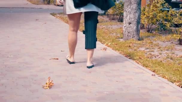 Woman wearing an orthopedic leg brace with adjustable straps to immobilise her leg following surgery or an accident walking outdoors — Stock Video