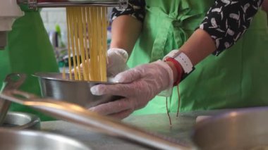 Pişirme master sınıfında makarna makinesi kullanarak hamurdan makarna yapan bir grup insan.