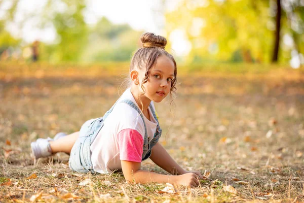 Porträtt av en liten flicka som ligger på en färgglad löv i höst parken — Stockfoto