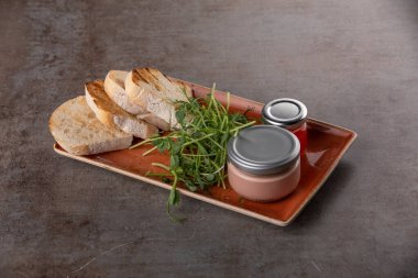 Cam kavanozda taze et ve gri masada kızarmış ekmek.