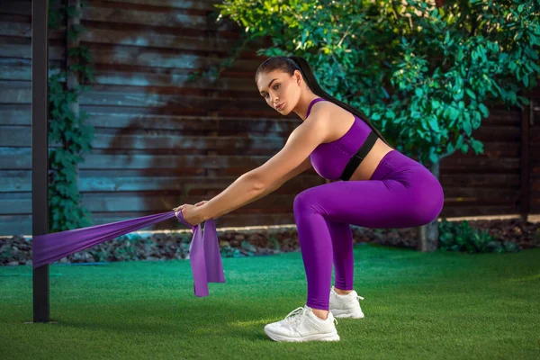 Giovane donna si allena con elastici all'aperto. Sano concetto di stile di vita attivo. ragazza che fa fitness nel parco — Foto Stock