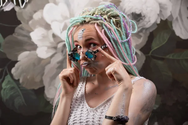 Elegante chica moderna con rastas multicolores en el fondo de la flor en gafas — Foto de Stock