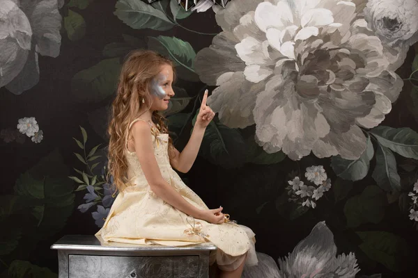 Маленькая девочка с нарисованным лицом на цветочном фоне — стоковое фото