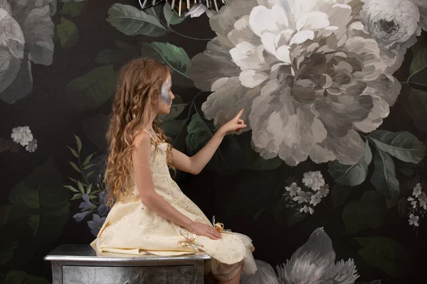 Маленькая девочка с нарисованным лицом на цветочном фоне — стоковое фото