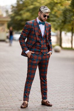 Yakışıklı genç işadamı kol saatini kontrol ediyor. Lüks takım elbiseli bir adam sokakta yürüyor.