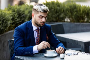 Düşünceli yakışıklı işadamı kafede kahve içip başka tarafa bakıyor.