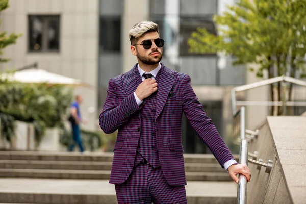 眼鏡をかけ髭を生やした若い実業家が階段を降りる 紫の豪華な3ピースのスーツを着た男 — ストック写真