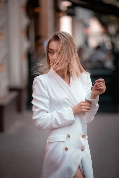 Porträt einer modischen Blondine, die in der Stadt weiße Jacke oder Blazer trägt und Haare entwickelt — Stockfoto