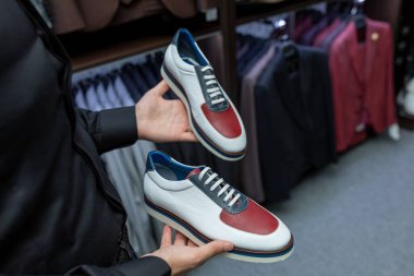 Erkek eller ayakkabıları elinde tutuyor. Yakından. Alıcıya pahalı ve modern çizmeler gösteren bir satıcı. Çevrimdışı Mağaza Konseri