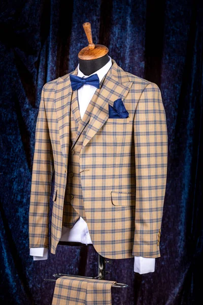 Mens business suit on mannequin, vintage color. elegant sand-colored three-piece suit in a cage with a bow tie and a scarf in a pocket