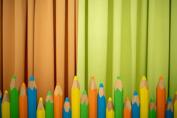 Crayons colorés sur fond vert et orange — Photo