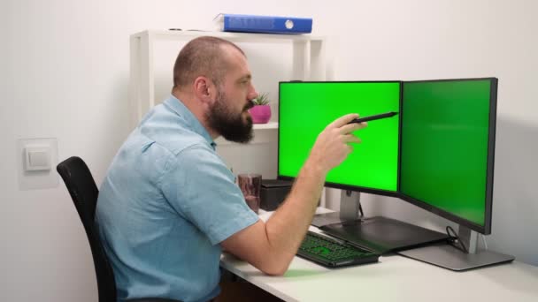 Hombre de negocios en casa. empleado decir en videoconferencia o videollamada sobre el nuevo proyecto apuntando en dos pantallas verdes o monitores. — Vídeos de Stock