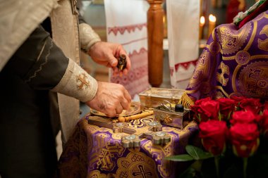 Rahibin ellerinde kutsal yağ. Rahip bir Hıristiyan Ortodoks kilisesinde Nebenk 'in vaftiz törenine hazırlanıyor.