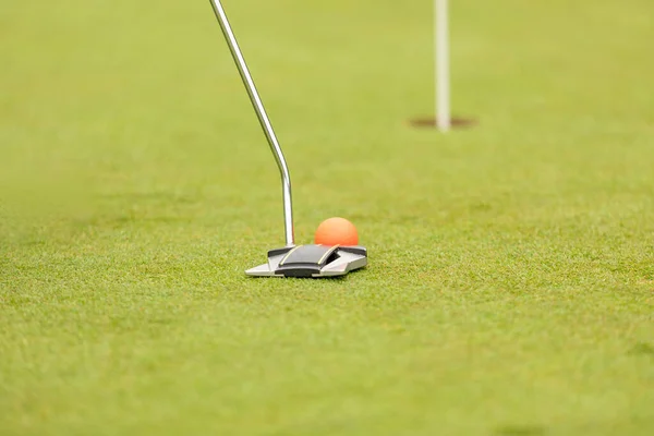 Putter golf club hammering a golf ball into a hole — Stock Photo, Image
