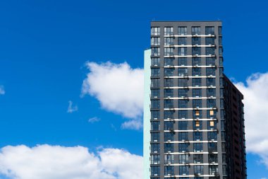 Güneşli bir günde, koyu mavi gökyüzü olan birçok penceresi ve balkonu olan modern, yüksek binalar.