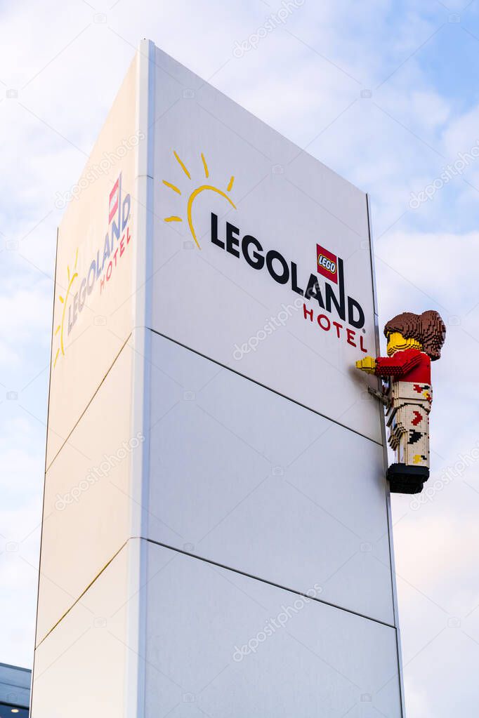 A colorful LEGO figure is seen climbing the Legoland Hotel Resort sign during a beautiful sunset in Billund Denmark, highlighting the playful spirit of this family-friendly destination.