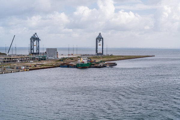 Контейнерный терминал Nordhavn строится в гавани Копенгагена Дания, а грузовое судно Famita загружает обломки на рабочем месте.