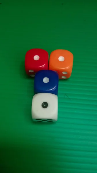 Yeşil desenli bir yüzeye dağılmış renkli zarlar.