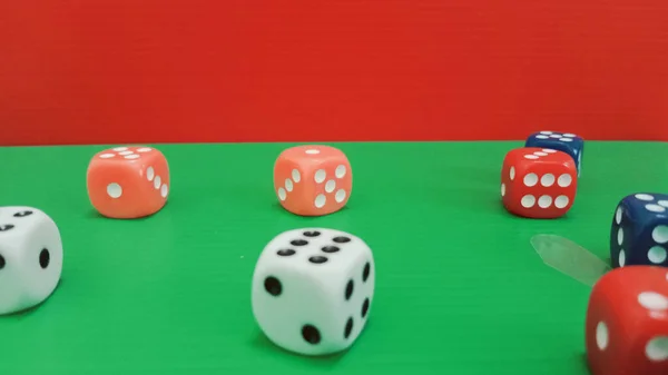 Kırmızı zarı olan yeşil bir yüzeye dağılmış renkli zarların yakın plan fotoğrafı.. 