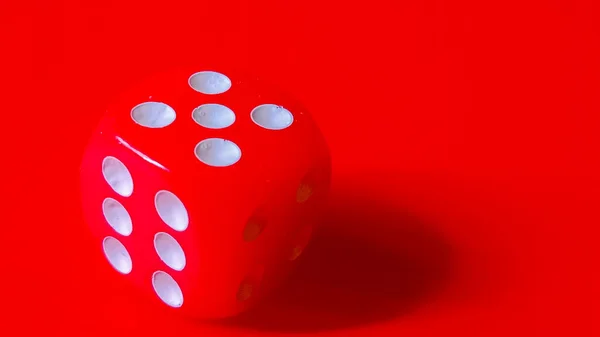 Canlı kırmızı zarlar beş numarayı gösteriyor, çizgili kırmızı bir zeminde dinleniyor..